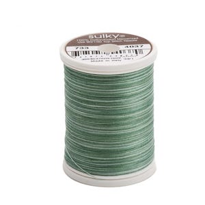 May include: A spool of Sulky 100% Cotton/Cotton Mercerized thread in color 733. The spool is green and white with the Sulky logo and the text "100% Cotton/Cotton Mercerized Use 90/100 Top Stitch Needle" printed on the label. The spool number is 4037.