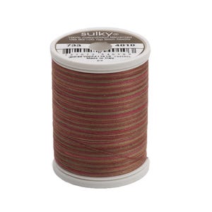 May include: A spool of Sulky 100% cotton/cotton mercerized thread in a brown, red, and green striped pattern. The spool is labeled with the number 733 and 4010. The text "Sulky 100% Cotton/Cotton Mercerized Use 80/100 Top Stitch Needles" is printed on the spool.