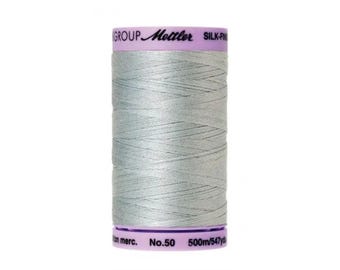 May include: A spool of light gray Mettler Silk-Finish thread with the text "GROUP Mettler SILK-FINISH" on the label. The spool is 500 meters (547 yards) long and is labeled "No. 50".