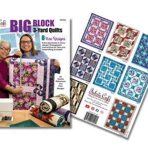 May include: A book cover titled "BIG BLOCK 3-Yard Quilts" with two women holding a quilt. The cover features the Fabric Cafe logo and text indicating 8 new quilt designs. A second page displays various quilt patterns. Rolled fabric and sewing supplies are also visible.