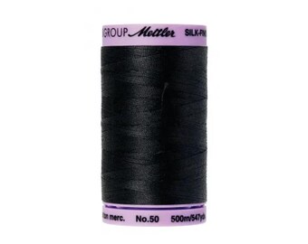 May include: A spool of black Mettler silk-finish thread. The spool has a purple top and bottom with white text that reads "Mettler SILK-FIN" and "No. 50 500m/547yd". The thread is tightly wound around the spool.