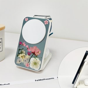 Könnte beinhalten: Ein weißer Ladeständer mit einem blauen und weißen Blumenmuster. Der Ständer hat eine runde Ladefläche für eine Uhr und eine rechteckige Ladefläche für ein Telefon. Der Ständer steht auf einer weißen Oberfläche mit einer Kerze und einem Band mit der Aufschrift "FeiMeiPresents Handmade".