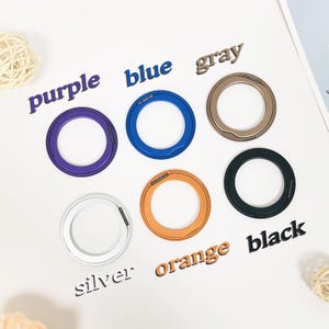 May include: Seven different colored metal rings with a small opening in each ring. The rings are labeled with the colors: purple, blue, gray, orange, black, and silver.