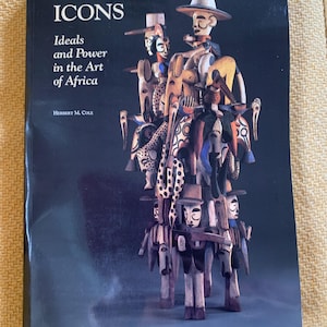 May include: A book titled "ICONS" with the subtitle "Ideals and Power in the Art of Africa" by Herbert M. Cole. The cover features a dark background and a sculpture composed of several carved wooden figures in various colors.
