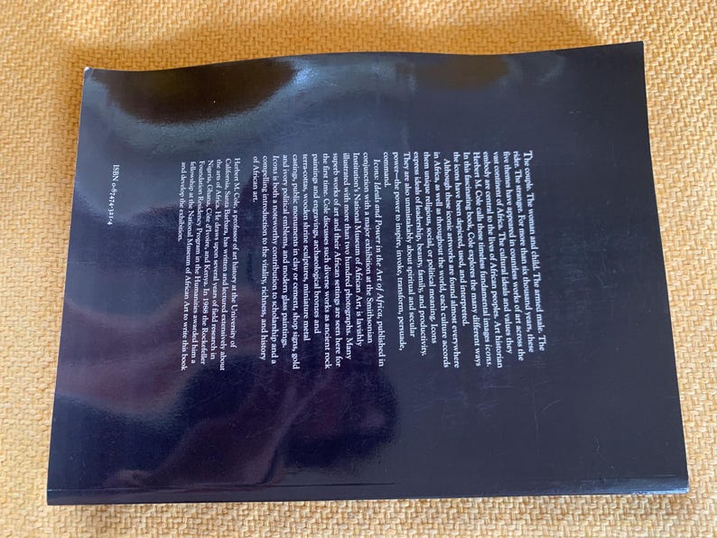 May include: A hardcover book titled "Icons: Ideals and Power in the Art of Africa." The book's cover is dark blue with text and a glossy finish. The book explores African art, featuring numerous photographs.