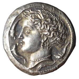 Puede incluir: Moneda de plata que muestra el perfil de una mujer con cabello rizado, collar y pendiente. La moneda tiene un relieve detallado y un borde irregular, posiblemente una antigüedad o una réplica, con un diámetro de aproximadamente 3 cm.