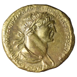 Puede incluir: Una moneda dorada que presenta el perfil de un hombre con una corona de laurel. La moneda tiene un trabajo de relieve detallado e inscripciones alrededor del borde. La superficie de la moneda tiene un aspecto ligeramente envejecido.