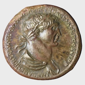 Puede incluir: Una moneda circular de color bronce que representa el perfil de una persona con una corona de laurel. El borde de la moneda tiene inscripciones. La moneda tiene un aspecto envejecido, con variaciones de color de marrón claro a bronce más oscuro.