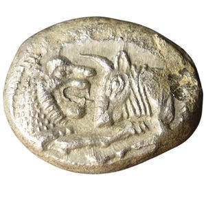 Könnte beinhalten: Eine Silbermünze mit geprägtem Design. Die Münze zeigt ein detailliertes Relief eines stilisierten Tieres, möglicherweise eines Bullen oder eines Pferdes, und andere abstrakte Elemente. Die Münze hat ein abgenutztes, antikes Aussehen.