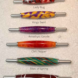 May include: Six 2-in-1 tools with silver metal ends and patterned acrylic barrels. The designs are labeled Lady Bug, Kings Swirl, Amethyst Geode, Chili Pepper, Rites of Spring, and Cafe au Lait. The text states: All 2 in 1 tools are same size.