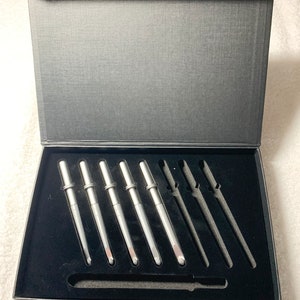 May include: A black box with a black velvet interior containing a set of 5 silver crochet hooks. The box has the text "Box of 5 hooks" printed on the bottom.