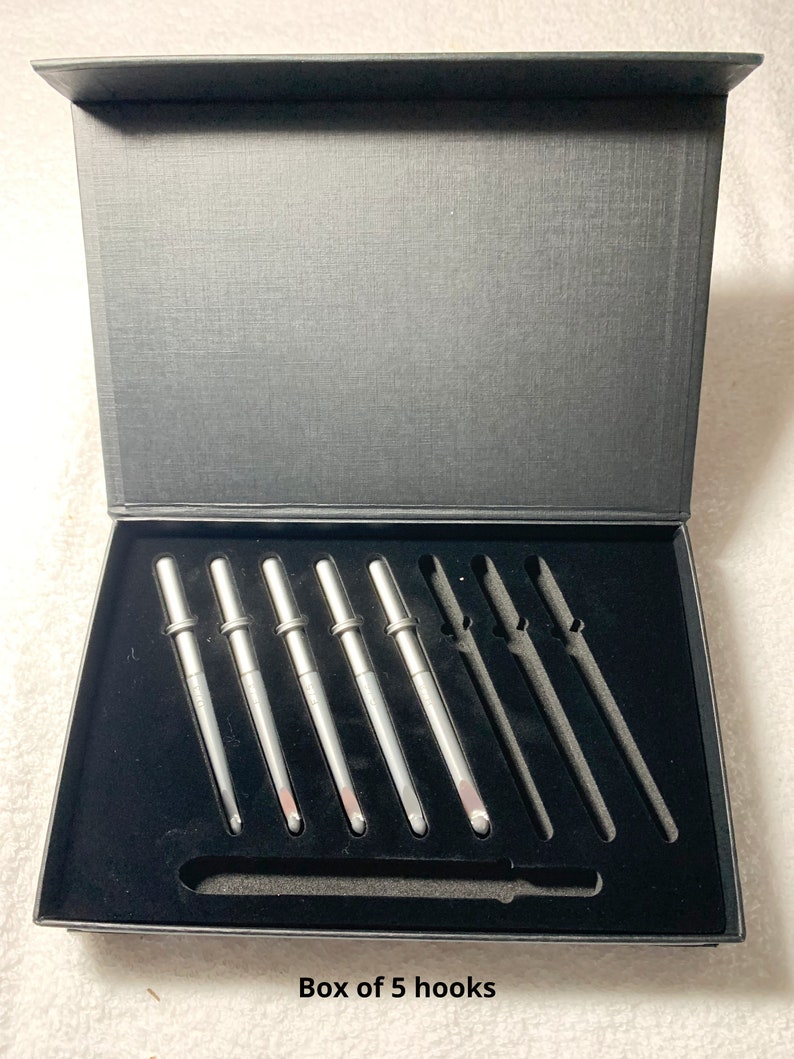 May include: A black box with a black velvet interior containing a set of 5 silver crochet hooks. The box has the text "Box of 5 hooks" printed on the bottom.