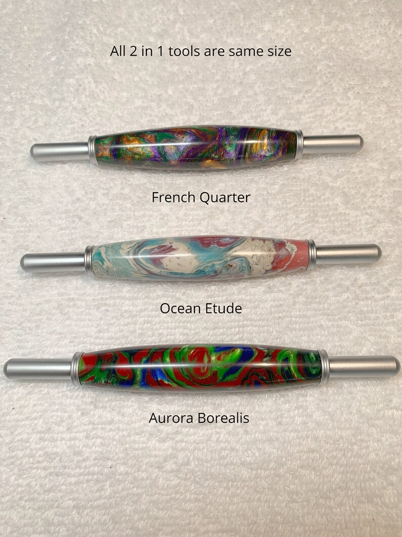 May include: Three wooden knitting needles with silver metal tips. The needles are decorated with colorful marbled patterns. The needles are labeled "French Quarter", "Ocean Etude", and "Aurora Borealis".