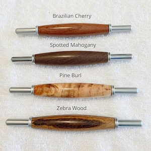 May include: Four wooden dowel rods with silver metal ends. The wood types are labeled: Brazilian Cherry, Spotted Mahogany, Pine Burl, and Zebra Wood.