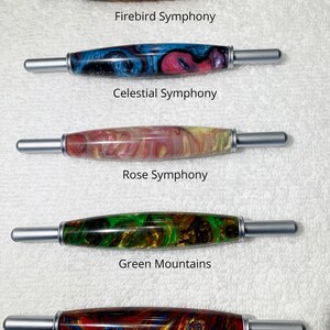 May include: Five different 2-in-1 tools with colorful, marbled wooden handles and silver metal ends. The tools are labeled "Firebird Symphony", "Celestial Symphony", "Rose Symphony", "Green Mountains", and "Dawn Symphony".