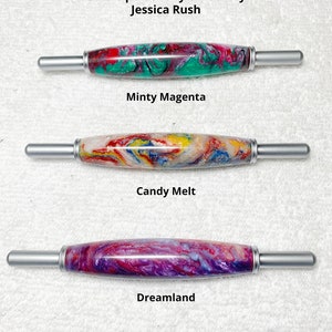 Op de afbeelding: Drie haaknaaldgrepen met verschillende kleurrijke gemarmerde patronen. De grepen zijn gelabeld met "Minty Magenta", "Candy Melt" en "Dreamland". De tekst "Gemaakt voor Oklaroots Kleuren persoonlijk gekozen door Jessica Rush" en "Alle grepen zijn dezelfde maat" is ook zichtbaar.