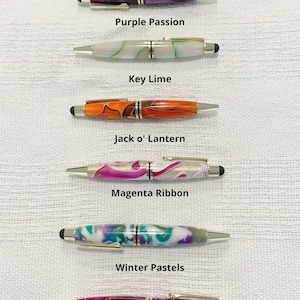 May include: Six pens with metallic accents and stylus tips, arranged vertically. The pens feature marbled patterns in purple, white with green, orange, magenta with white, multi-colored pastels, and amethyst swirl. Text labels identify each color.