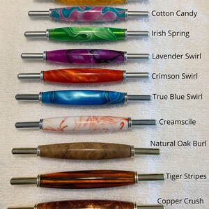 May include: Ten seam rippers with decorative handles in various colors and patterns, labeled Sunshine Yellow, Cotton Candy, Irish Spring, Lavender Swirl, Crimson Swirl, True Blue Swirl, Creamsicle, Natural Oak Burl, Tiger Stripes, and Copper Crush.