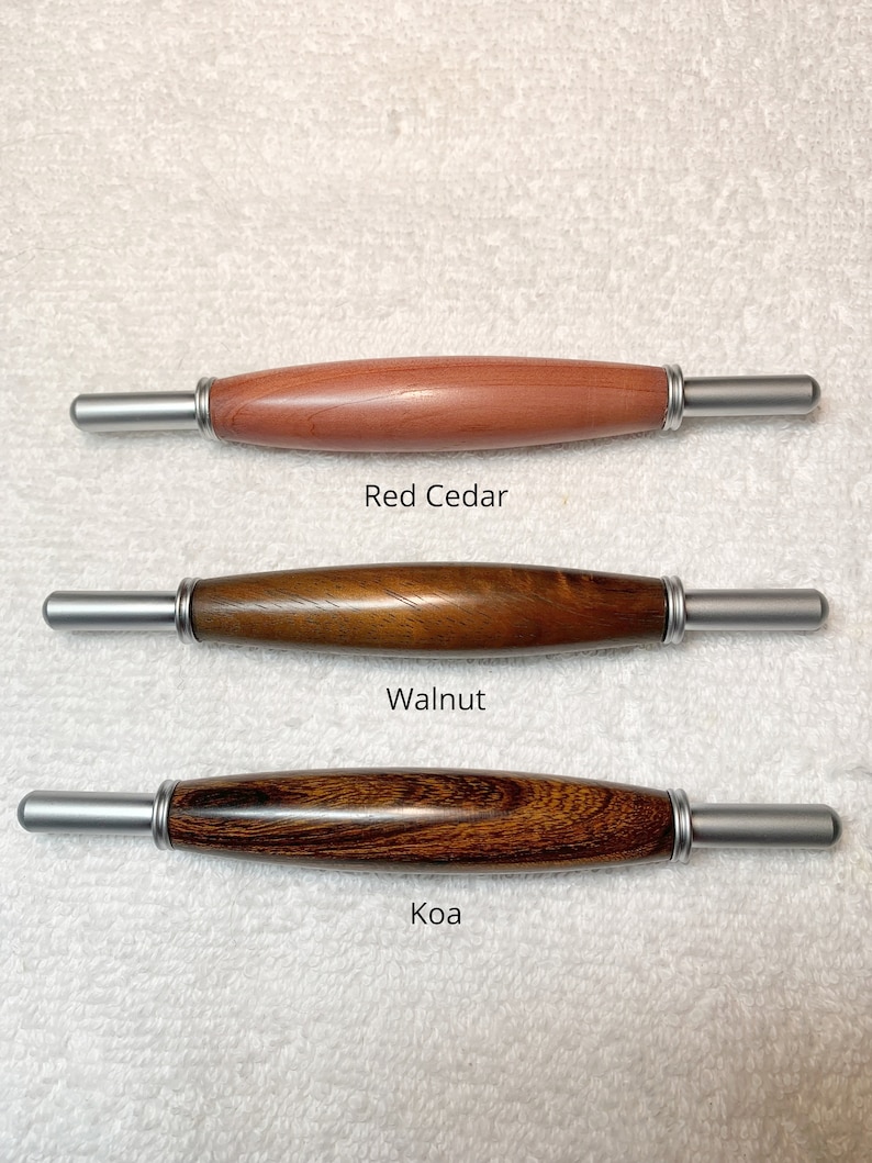 May include: Three wooden seam rippers with silver metal ends. The top tool is labeled Red Cedar, the middle is Walnut, and the bottom is Koa. Each tool features a smooth, rounded wooden handle with a polished finish and silver metal ferrules.