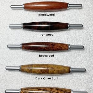 May include: Five wooden tools with silver metal tips, each with a different wood grain pattern. The wood types are labeled: Bloodwood, Ironwood, Rosewood, Dark Olive Burl, and Bicote.