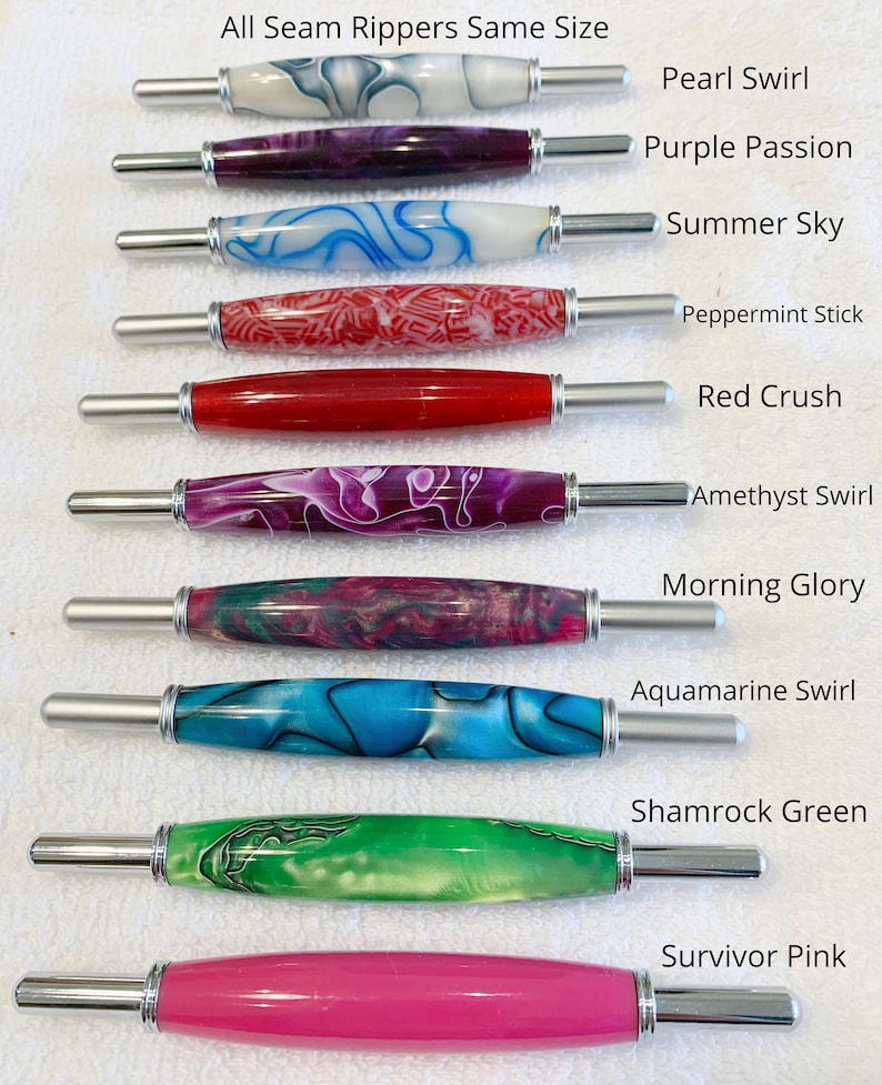 May include: Ten seam rippers with decorative acrylic handles in various colors and patterns, labeled Pearl Swirl, Purple Passion, Summer Sky, Peppermint Stick, Red Crush, Amethyst Swirl, Morning Glory, Aquamarine Swirl, Shamrock Green, and Survivor Pink.
