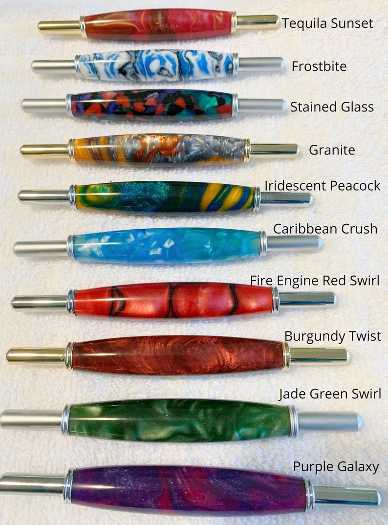 May include: Ten seam rippers with colorful resin handles and metal ends. The handles feature patterns labeled Tequila Sunset, Frostbite, Stained Glass, Granite, Iridescent Peacock, Caribbean Crush, Fire Engine Red Swirl, Burgundy Twist, Jade Green Swirl, and Purple Galaxy.