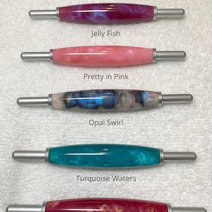 May include: Five cylindrical tools with metallic silver ends and polished resin barrels in various colors. The text reads: All handles are same size, Jelly Fish, Pretty in Pink, Opal Swirl, Turquoise Waters, and Dawn Blush. Each barrel features a unique marbled or pearlescent finish in shades of magenta, pink, blue, turquoise, and red with gold accents.
