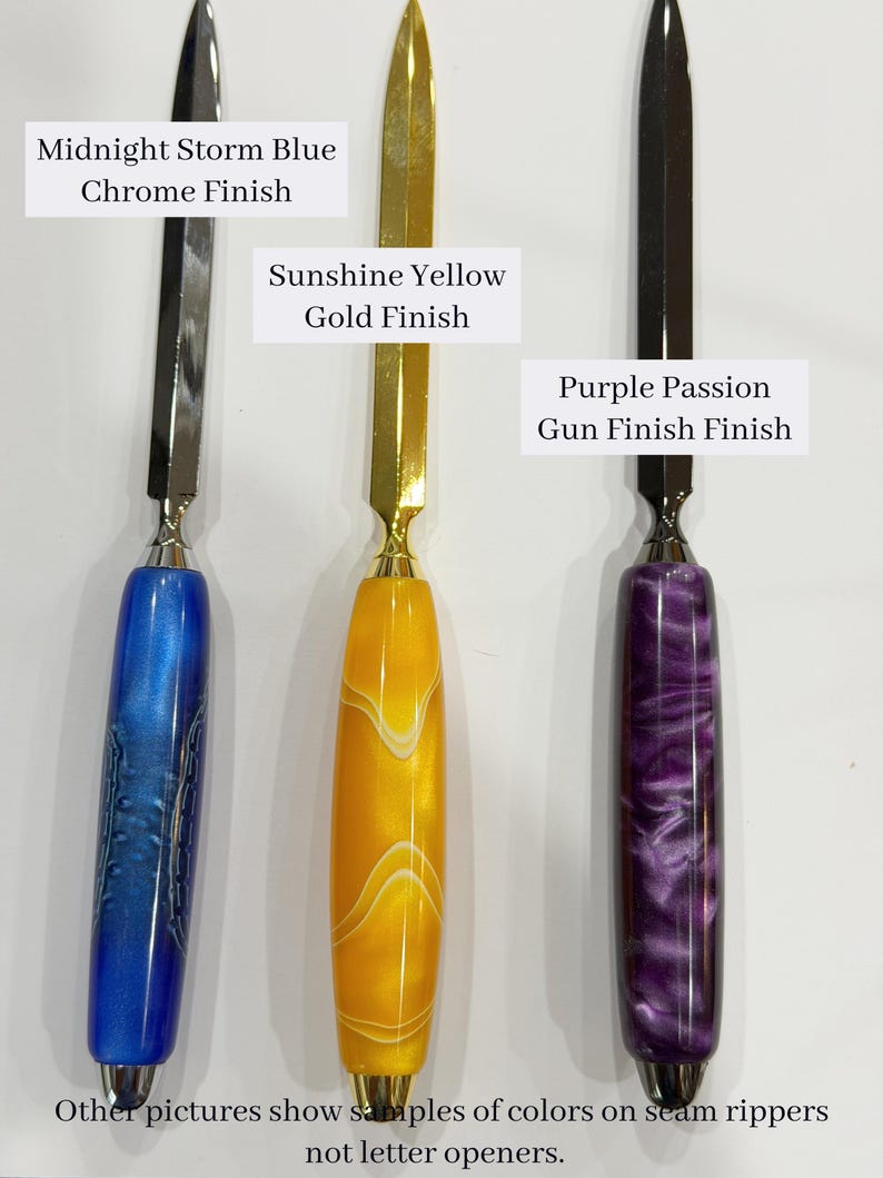May include: Three letter openers with metallic blades and cylindrical handles. The left has a blue handle with a chrome finish blade labeled Midnight Storm Blue Chrome Finish. The center is yellow with a gold finish blade labeled Sunshine Yellow Gold Finish. The right is purple with a gunmetal finish blade labeled Purple Passion Gun Finish Finish. Text at the bottom reads: Other pictures show samples of colors on seam rippers not letter openers.