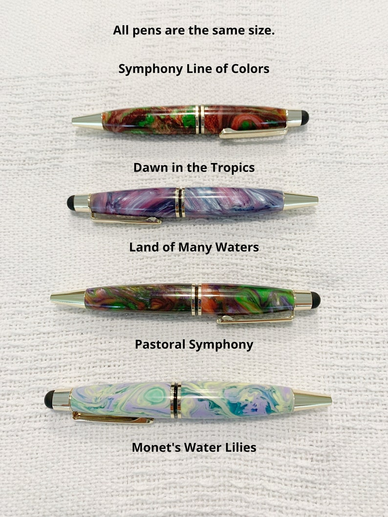 May include: Four pens from the Symphony Line of Colors, each with a unique marbled resin barrel and gold-tone accents. The pens are labeled Dawn in the Tropics, Land of Many Waters, Pastoral Symphony, and Monet's Water Lilies. All pens are the same size.