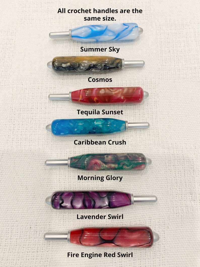 May include: Seven crochet hooks with marbled resin handles in various colors, including blue, black, red, teal, green, purple, and fire engine red. Each handle features a silver metal hook tip. Text labels identify the colors as Summer Sky, Cosmos, Tequila Sunset, Caribbean Crush, Morning Glory, Lavender Swirl, and Fire Engine Red Swirl. The text states all crochet handles are the same size.