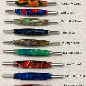 May include: Ten different wooden pens with various colorful patterns and designs. The pens are arranged vertically with the names of each pattern listed to the right of each pen. The names of the patterns are: Zebra Wood, Rainbow Camo, Old Glory, Pearl Rainbow, The Abyss, Viking Storm, Bahama Seas, Flamin' Funk, Deep Blue Sea, and Cinnamon Roll.