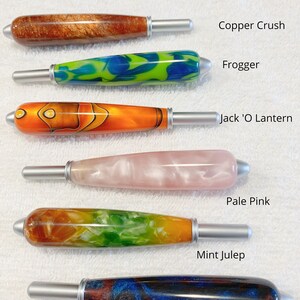 May include: Six cylindrical handles with silver-toned metal tips, labeled Copper Crush, Frogger, Jack 'O Lantern, Pale Pink, Mint Julep, and Andromeda Galaxy. The text states: All handles are the same size. Each handle features a unique resin pattern.