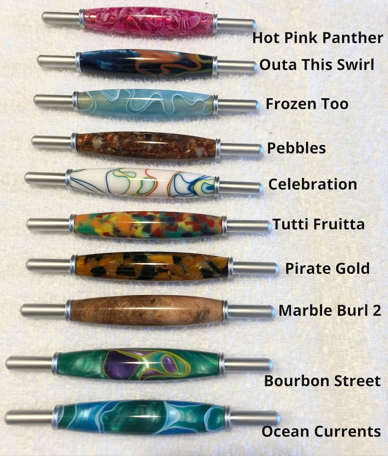 May include: Ten different colored and patterned crochet hooks with silver handles. The hooks are labeled with names such as "Hot Pink Panther", "Outa This Swirl", "Frozen Too", "Pebbles", "Celebration", "Tutti Fruitta", "Pirate Gold", "Marble Burl 2", "Bourbon Street", and "Ocean Currents".