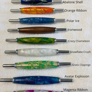 May include: Ten double-ended seam rippers with decorative barrels labeled Pink Redbud Wood, Abalone Shell, Orange Ribbon, Polar Ice, Ironwood, Crazy Chameleon, Snowflake Crush, Grass Clippings, Avatar Explosion, and Magenta Ribbon.