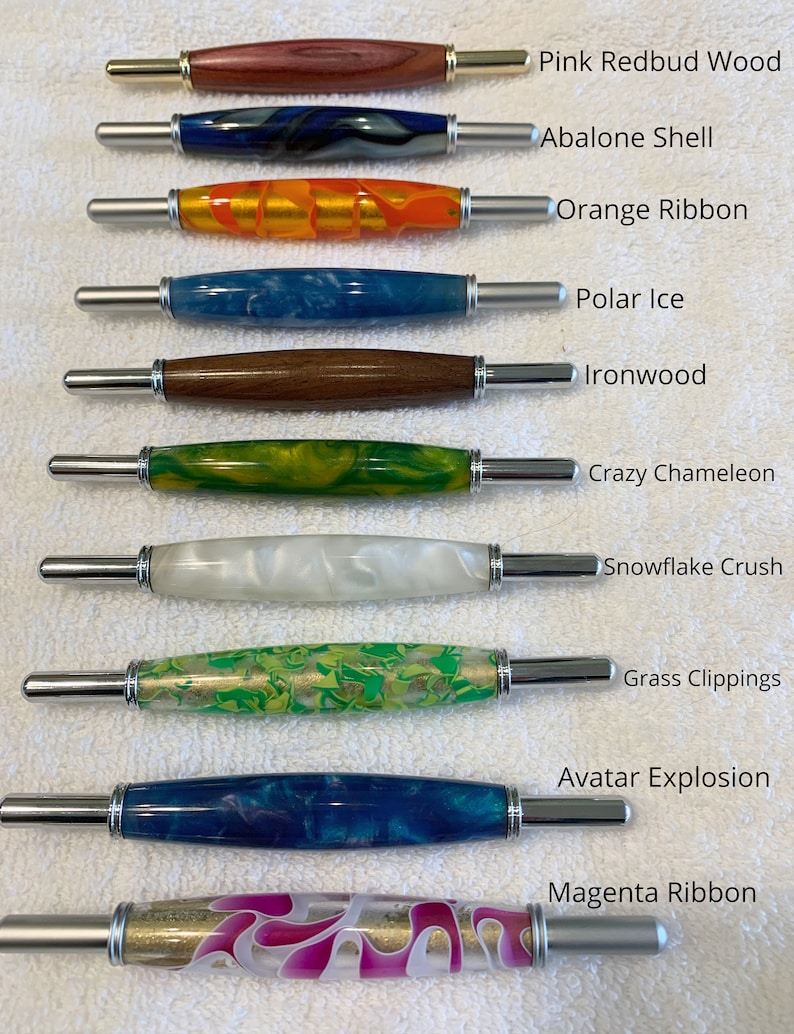 May include: Ten double-ended seam rippers with decorative barrels labeled Pink Redbud Wood, Abalone Shell, Orange Ribbon, Polar Ice, Ironwood, Crazy Chameleon, Snowflake Crush, Grass Clippings, Avatar Explosion, and Magenta Ribbon.