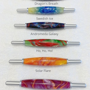 May include: Six different colored crochet hooks with silver handles. The hooks are labeled with names like "Dragon's Breath", "Swedish Ice", "Andromeda Galaxy", "Ho, Ho, Ho!", "Solar Flare", and "Ultra Violet".