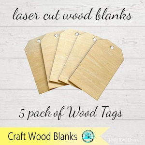 May include: A pack of five laser-cut wood tags. Each tag is a light tan color with a hole at the top for stringing. The text "laser cut wood blanks" and "5 pack of Wood Tags" are displayed in black script. The words "Craft Wood Blanks" are also visible.