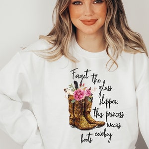 May include: White sweatshirt with a graphic of cowboy boots and the text "Forget the glass slipper, this princess wears cowboy boots."