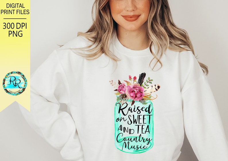 May include: White sweatshirt with a teal mason jar design featuring pink flowers and feathers. The jar has the text "Raised on Sweet and Tea Country Music".