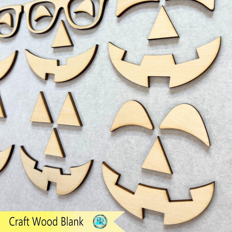 K&ouml;nnte beinhalten: Holzzuschnitte f&uuml;r Halloween-Bastelarbeiten. Das Bild zeigt verschiedene ausgeschnittene Formen von K&uuml;rbisgesichtern, einschlie&szlig;lich Augen, Nasen und M&uuml;nder. Der Text "Craft Wood Blank" ist unten links sichtbar.