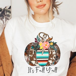 May include: A white t-shirt with a colorful patchwork pumpkin design and the text "It's Fall Y'all".