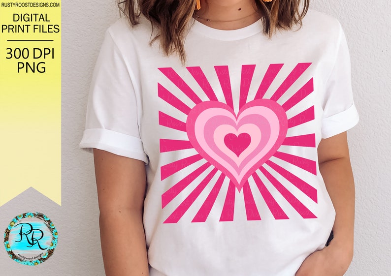 May include: A white t-shirt with a pink heart design. The heart is layered with concentric circles of pink and has a sunburst pattern behind it.