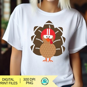 May include: A white t-shirt with a cartoon turkey wearing a football helmet and a brown and white patterned body. The turkey is surrounded by brown footballs with white laces.