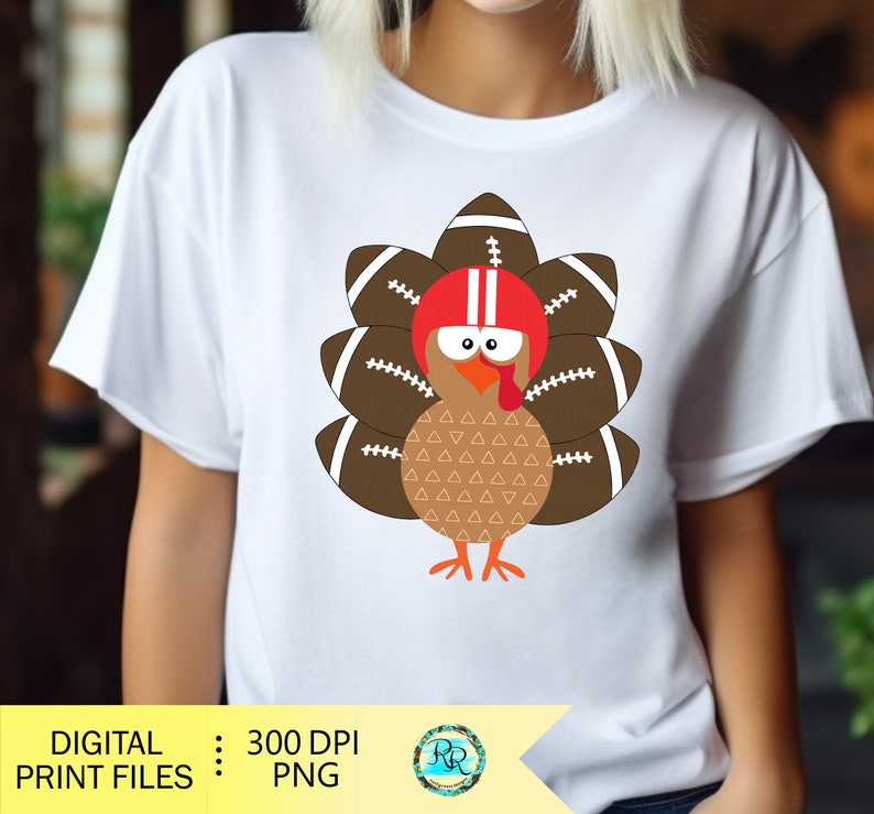 May include: A white t-shirt with a cartoon turkey wearing a football helmet and a brown and white patterned body. The turkey is surrounded by brown footballs with white laces.