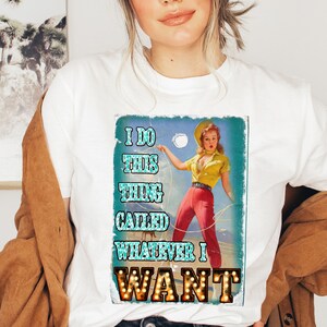 K&ouml;nnte beinhalten: Wei&szlig;es T-Shirt mit einem Retro-Grafik einer Frau in Gelb und Rot, die ein Seil h&auml;lt. Die Grafik zeigt "I DO THIS THING CALLED WHATEVER I WANT". Das Bild hat einen Vintage-Look.