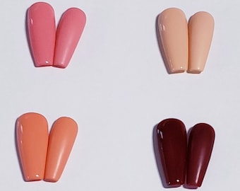 May include: A collection of twelve pairs of glossy, coffin-shaped press-on nails arranged in a grid. The colors include pink, peach, yellow, orange, maroon, magenta, dark red, light blue, royal blue, teal, dark green, and solid black.