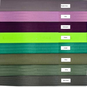 May include: A collection of eight fabric swatches in various shades of purple, green, and brown. The swatches are labeled with the following names: Purple Haze, Lilac, Aubergine, Grass, Jungle, Olive, Army, and Rich Olive.