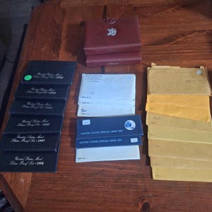 May include: A collection of United States Mint Silver Proof Sets and Special Mint Sets. The sets are in their original packaging, including black boxes and envelopes. Years visible include 1993, 1994, 1995, 1997, and 1998.