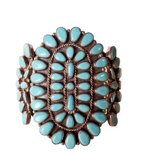 May include: A turquoise and silver Native American bracelet with a cluster of turquoise stones in a floral pattern.