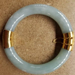 May include: A light blue jade bangle bracelet with a gold clasp.